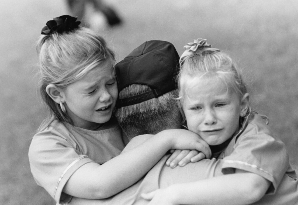 Two young children crying and embracing a parent — San Francisco wrongful death lawyer John J. Roach