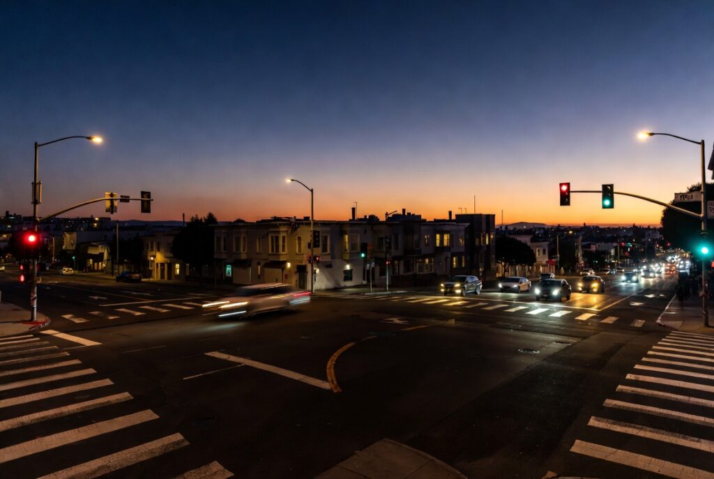 Unprotected left turn across oncoming traffic at a San Francisco intersection at dusk