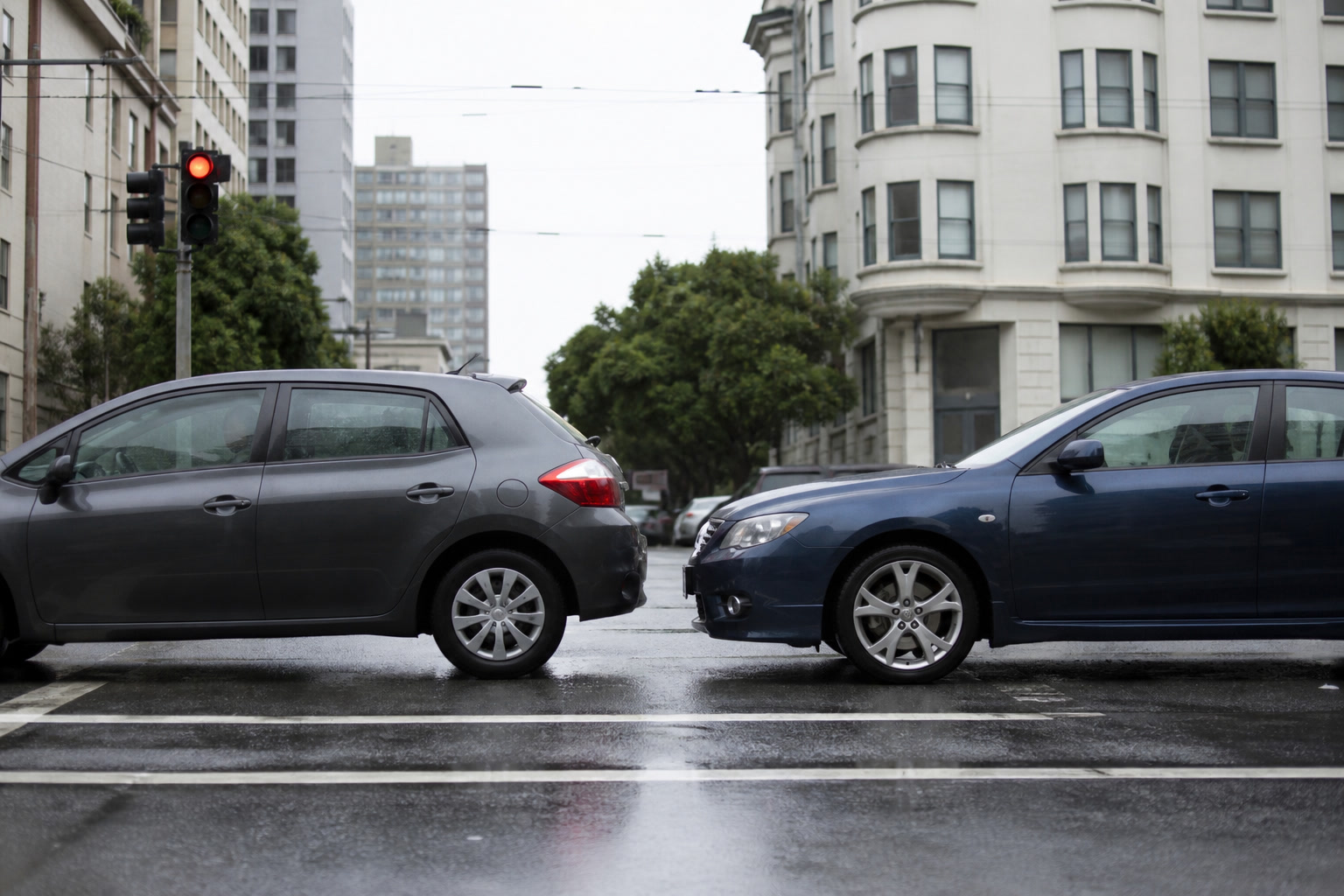 Low-speed rear-end of two cars at a red light on a wet San Francisco street